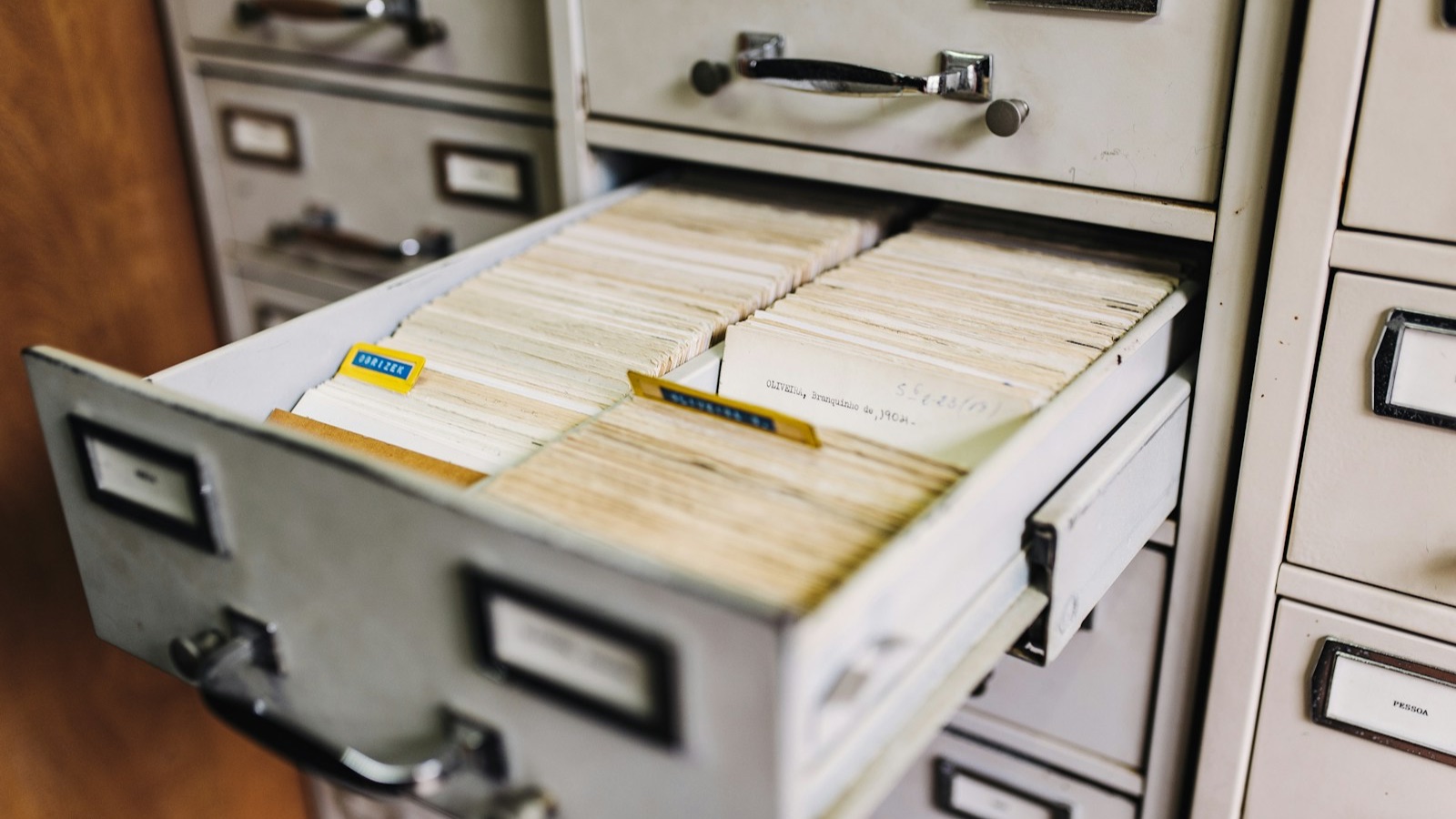 An open drawer of a filing cabinet packed with old index cards