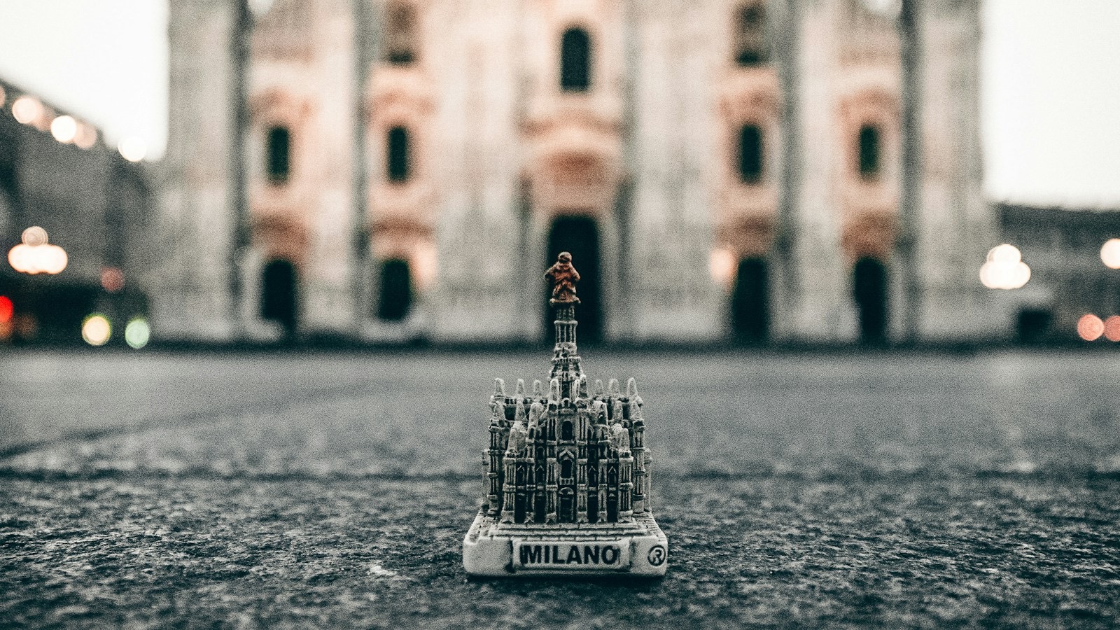 A small souvenir model of Milan Cathedral on the ground in front of the real cathedral